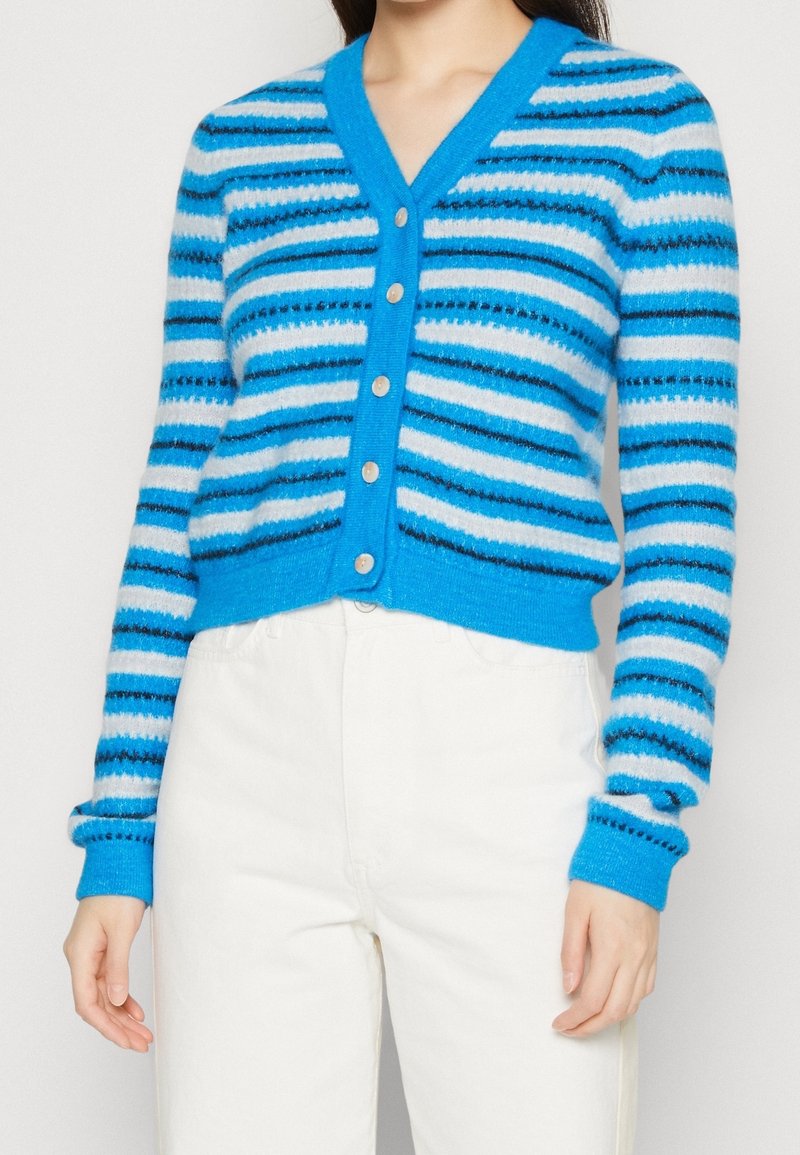 Cardigan rayé bleu avec un col en V, présentant des rayures alternées de différentes nuances de bleu, de blanc et de noir, et six boutons de couleur claire. Texture douce.