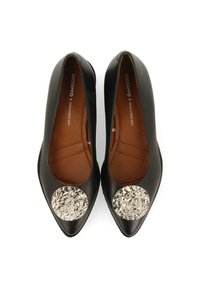 Escarpins en cuir noir à bout pointu, dotés d'un accent circulaire argenté métallique à l'avant. Texture lisse, design élégant.
