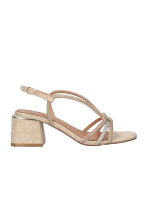 Sandalia beige con tacón bajo y ancho, con correa en el tobillo, tiras de pedrería anudadas sobre los dedos y detalle metálico en el tacón.