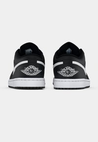 Black leather sneakers with white accents, round toe, padded collar, and Air Jordan logo embroidered on the heel. Flat rubber sole.