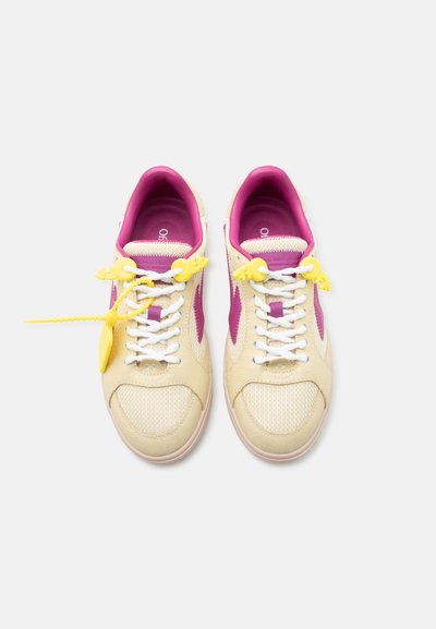 Κρέμ και ματζέντα αθλητικά παπούτσια με λευκά κορδόνια και κίτρινες διακοσμητικές ετικέτες σε απλό λευκό φόντο.