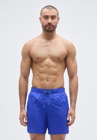 Μαγιό σορτς σε έντονο μπλε ύφασμα με κορδόνι στη μέση και τυρκουάζ λεπτομέρειες, με ελαφρύ και υφασμένο σχέδιο.