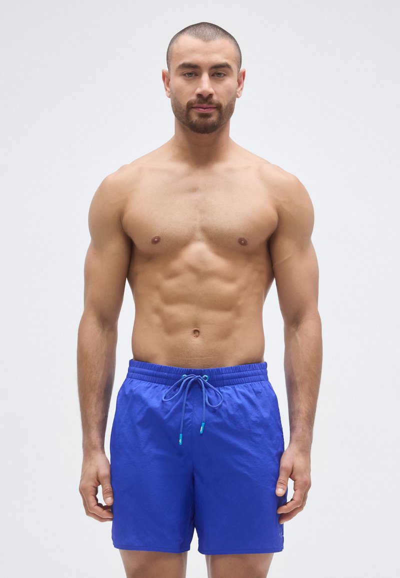 Μαγιό σορτς σε έντονο μπλε ύφασμα με κορδόνι στη μέση και τυρκουάζ λεπτομέρειες, με ελαφρύ και υφασμένο σχέδιο.