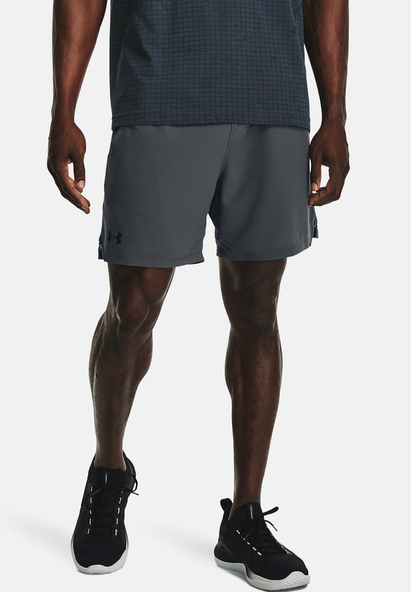 Pantalones cortos deportivos grises confeccionados con una tela ligera, con un acabado suave y un branding sutil. Combinados con zapatos deportivos negros.