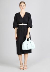 Musta, polvipituinen mekko, jossa on V-muotoinen kaula-aukko, puffi hihat ja hopearitssi. Yhdistetty vaaleansiniseen käsilaukkuun ja paljaisiin korkokenkiin.