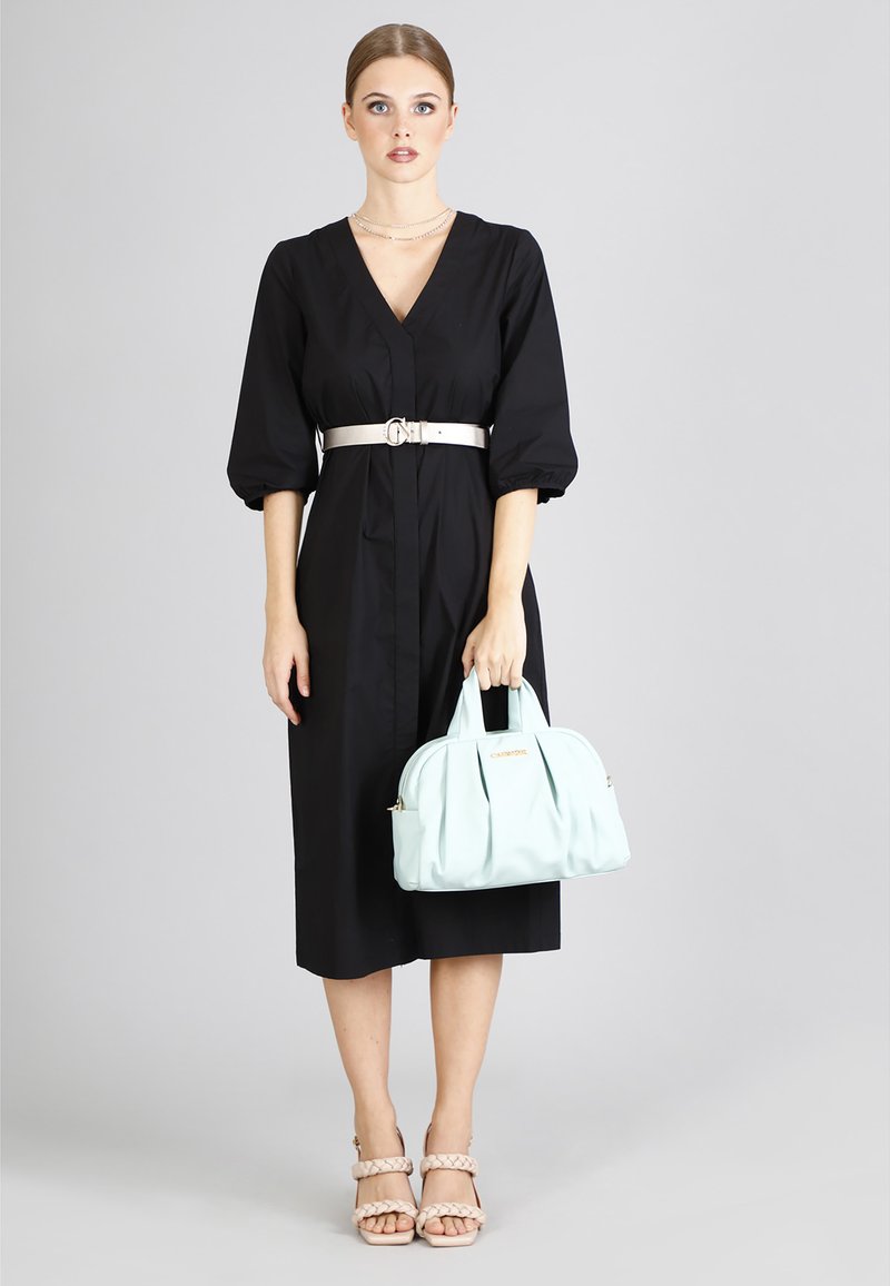 Musta, polvipituinen mekko, jossa on V-muotoinen kaula-aukko, puffi hihat ja hopearitssi. Yhdistetty vaaleansiniseen käsilaukkuun ja paljaisiin korkokenkiin.