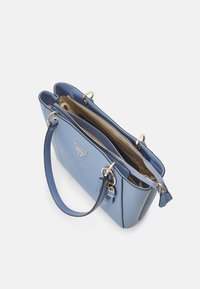 Torebka typu tote w kolorze niebieskim z nieba, wykonana ze skóry, z elementami ze złotego metalu, dwiema otwartymi kieszeniami i zapięciem na zamek. Posiada zawieszkę oraz logo marki.