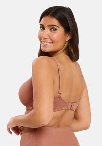 Soutien-gorge rose avec un design texturé, bretelles réglables et fermeture à crochet et œillet au dos. Avec des accents subtils pour les détails.