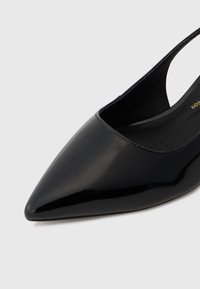 Black patent leather slingback shoe with a pointed toe and a cutout design; smooth, glossy finish with minimal hardware details.