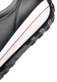 Semelle de chaussure en cuir noir avec une semelle intermédiaire blanche et une fine bande rouge, dotée d'une bande de roulement en caoutchouc noir texturé pour l'adhérence et la durabilité.