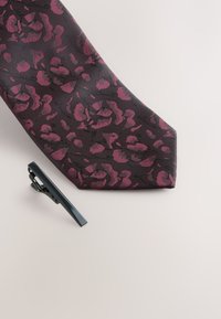 Dunkle Krawatte mit floralem Muster in Burgunder- und Schwarztönen. Begleitet von einer eleganten schwarzen Krawattenklammer. Strukturierter Stoff.