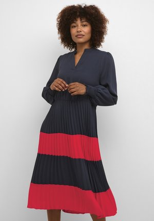Navy blue and red pleated dress with a V-neck, long sleeves, and smocked cuffs, featuring horizontal color blocks in a flowing design.