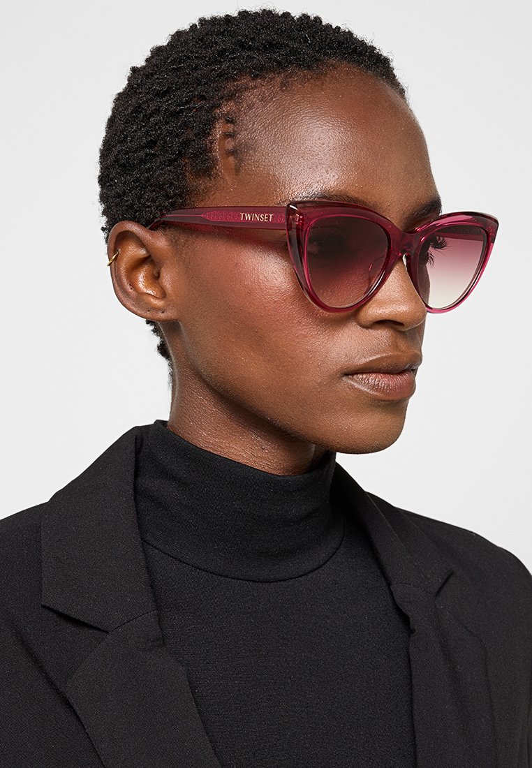 Katzenaugen-Sonnenbrille aus durchscheinendem burgunderfarbenem Kunststoff mit Verlaufsgläsern. Das Gestell verfügt über ein dezentes Markenlogo am Bügel.