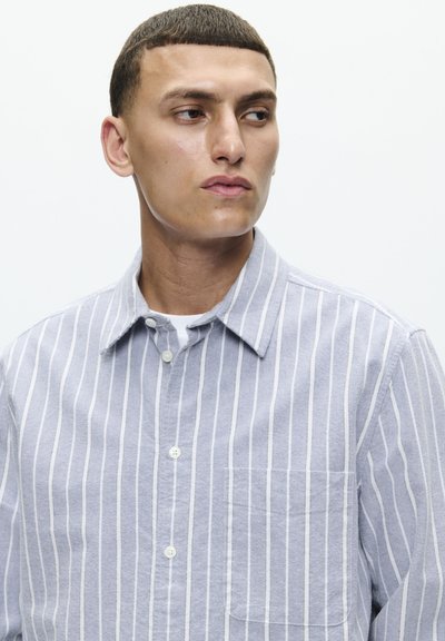 Chemise à manches courtes en tissu bleu clair avec des rayures verticales blanches, dotée d'un col classique et d'une poche poitrine unique.