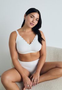 Bralette blanche avec bordure festonnée et tissu doux, accompagnée d'un slip blanc assorti. Texture lisse, design simple, et sans détails en métal.