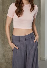 Rosa kortärmad t-shirt, med en liten Nike-logotyp. Kombineras med vida grå rutiga byxor. Slät textur.