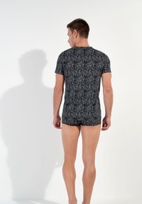 Black short-sleeve shirt with a white floral pattern, fitted design, and crew neck, worn with matching shorts. Fabric appears soft and stretchy.