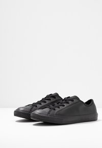 Sneakers neri in pelle liscia, con design a bassa altezza, punta tondeggiante, chiusura con lacci e suola in gomma texturizzata.