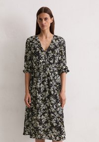 Schwarz geblümt Kleid mit V-Ausschnitt, weißen und gelben Blumenmustern und 3/4-Ärmeln. Glattes Gewebe mit einer taillierten Taille.