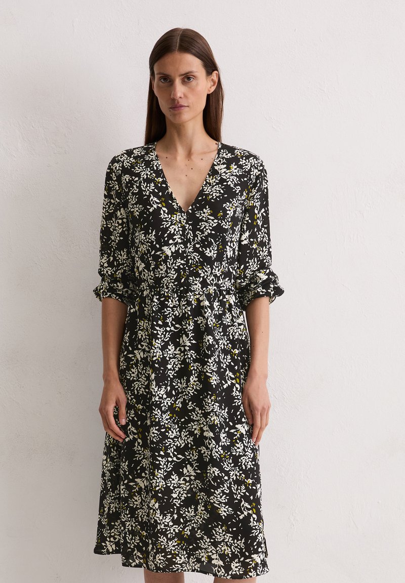 Schwarz geblümt Kleid mit V-Ausschnitt, weißen und gelben Blumenmustern und 3/4-Ärmeln. Glattes Gewebe mit einer taillierten Taille.