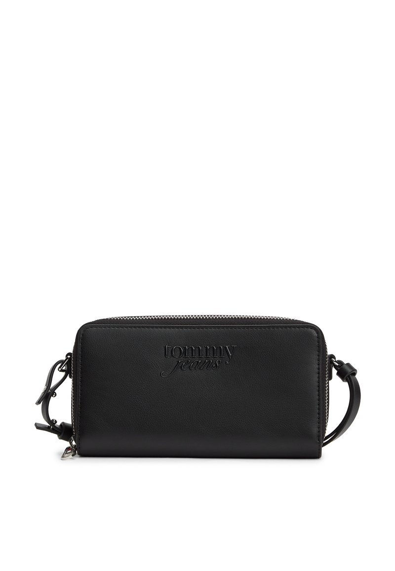 Μαύρο δερμάτινο πορτοφόλι με ανάγλυφο λογότυπο "tommy jeans", ορθογώνιο σχήμα, κλείσιμο με φερμουάρ και αποσπώμενο λουράκι. Λείο υλικό, μινιμαλιστικός σχεδιασμός.