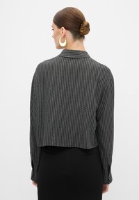 Afgekorte zwart-wit gestreepte lange mouwen shirt met een kraag, met een relaxte pasvorm en aangeknoopte mouwmanchetten.