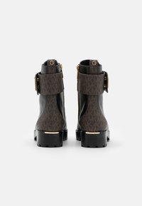 Sorte og brune ankelstøvler med et mønstret læderdesign, guldfarvet hardware og en lynlås i siden. Kraftig sål med detaljer.