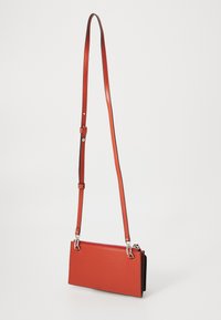 Rote Leder-Crossbody-Tasche mit verstellbarem Riemen, Reißverschluss und silberfarbenen Hardware-Akzenten. Glatte Textur, rechteckige Form mit minimalistischem Design.