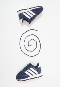 Mörkblå nät-sneakers med vita ränder, en texturerad ovandel, rund tå och en svart gummisole. Inkluderar en spiralformad marinblå skosnöre.