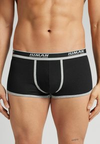Boxer shorts de rayas negras con una cinturilla elástica gris que presenta el nombre de la marca. El diseño incluye un soporte frontal y costuras en contraste.