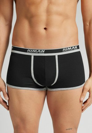 Boxers en noir à côtes avec une ceinture élastique grise arborant le nom de la marque. Le design comprend une poche avant de soutien et des coutures contrastantes.