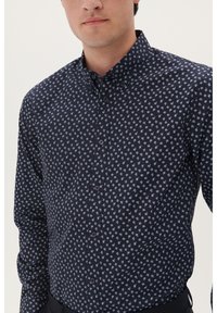 Marineblauwe overhemd met bloemenpatroon; gemaakt van een soepele stof, met een kraag en donkere knopen, getailleerd bij de taille.