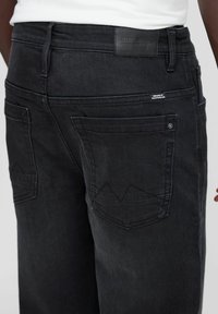 Vaqueros de mezclilla negra con corte recto, que presentan dos bolsillos traseros con detalles de costura triangular y una etiqueta de cuero con la marca en la cinturilla.