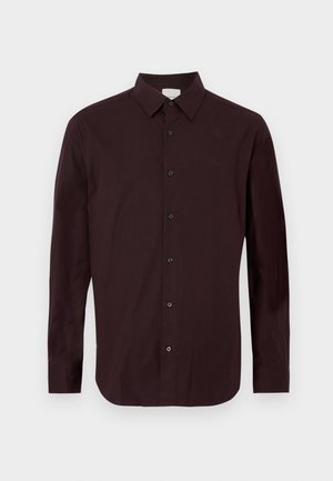 Viininpunainen pitkähihaispaita, valmistettu sileästä kankaasta. Siinä on napillinen kaulus ja viisi mustaa nappia edessä. Hienovarainen logo rinnassa.