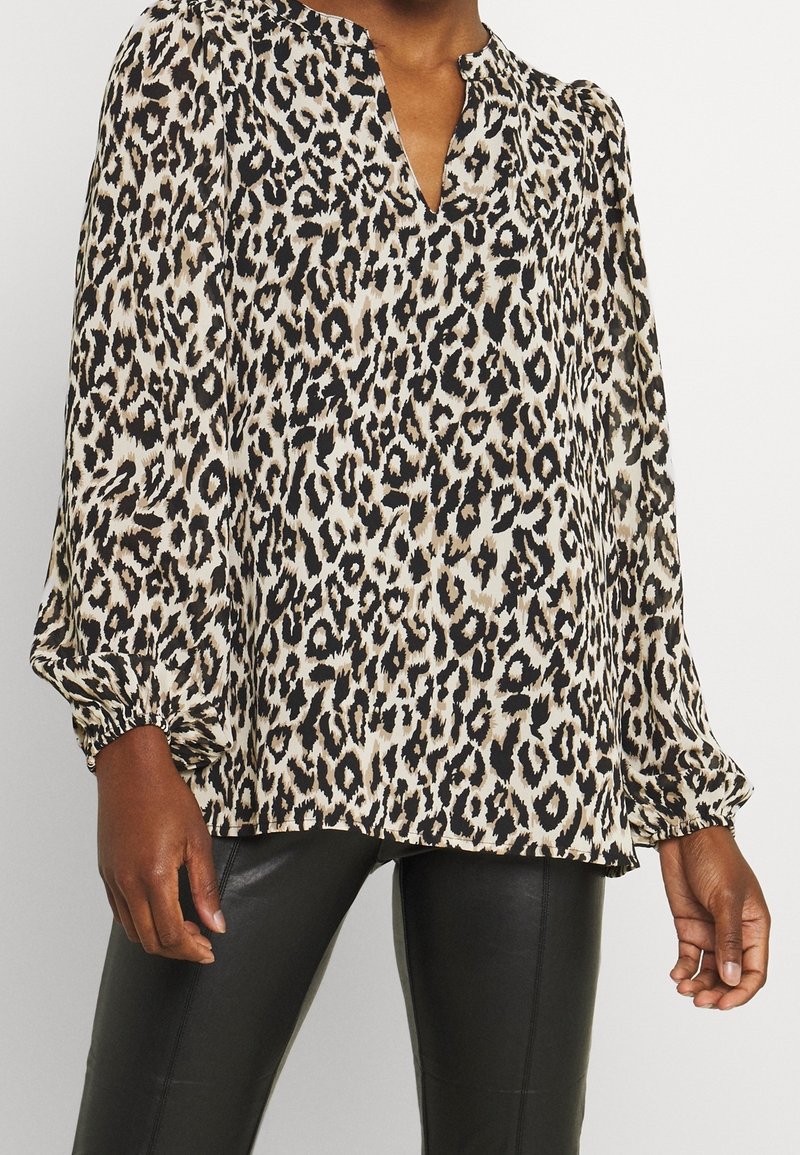 Leopardmönstrad blus i lättviktsmaterial, med V-ringning, långa puffärmar med elastiska manschetter och lös passform. Färgerna svart, beige och brunt.