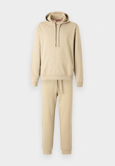 Ensemble de sweat à capuche et de joggers beige en tissu doux. Le sweat à capuche comporte un cordon de serrage et une poche frontale ; les joggers ont une taille élastique.