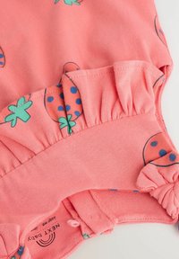 Combinaison bébé rose corail avec imprimé fraise et feuille, dotée de manches volantées et de boutons-pression en bas pour un changement facile.