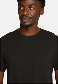 T-shirt in cotone nero con scollo rotondo e maniche corte; presenta un elegante logo sulla parte anteriore. Texture liscia e taglio classico.