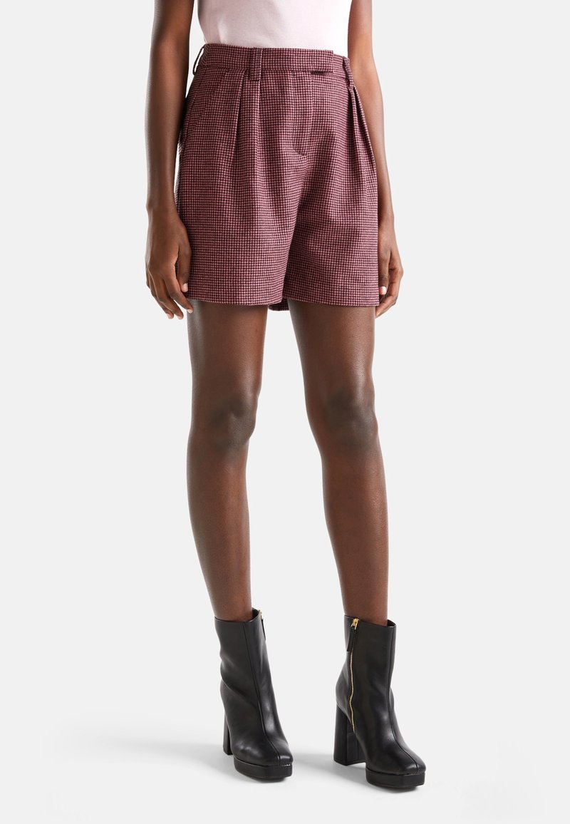 Punaiset ja valkoiset ruudulliset shortsit, joissa on poimutettu muotoilu, korkea vyötärö, sivutaskut ja sileä pinta, yhdistetty mustiin korkokenkiin.