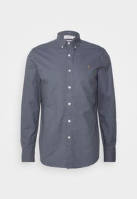 Ciemnoszara koszula na guziki z kołnierzykiem, długimi rękawami i małym złotym logo na piersi. Posiada białe guziki i gładką teksturę tkaniny.