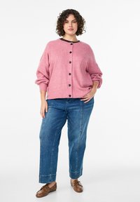 Rožinis ribuotas kardiganas su juodais mygtukais, dėvimas virš tamsiai mėlynų džinsų. Kardiganas turi apvalų kaklo iškirptę ir pūstus rankovus. Ruda avalynė papildo šį įvaizdį.