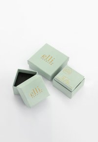 Muntgroene dozen met gouden "elli" branding. Eén doos is open en onthult een zwarte binnenkant. Er zijn nog twee gesloten dozen aanwezig.