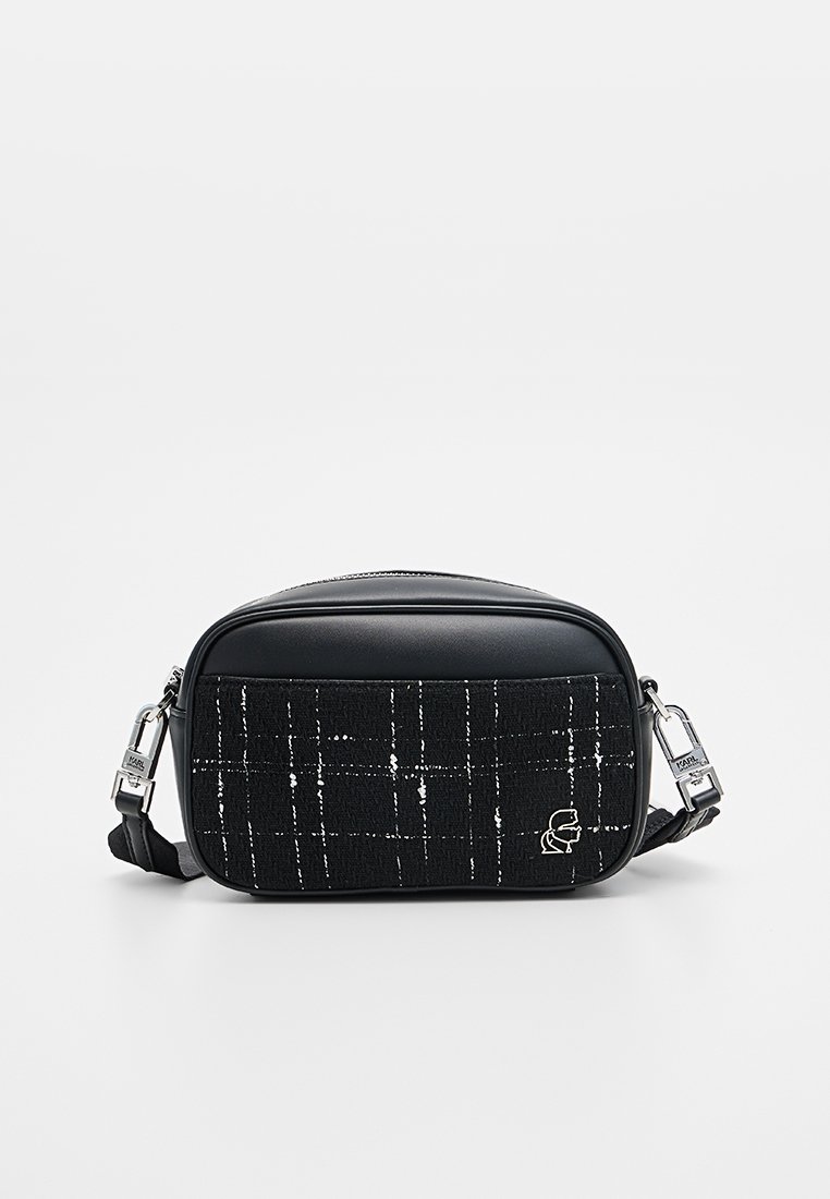 Bolso bandolera negro con un panel de tela texturizada con un patrón de cuadros, detalles en cuero negro y una correa ajustable y desmontable.