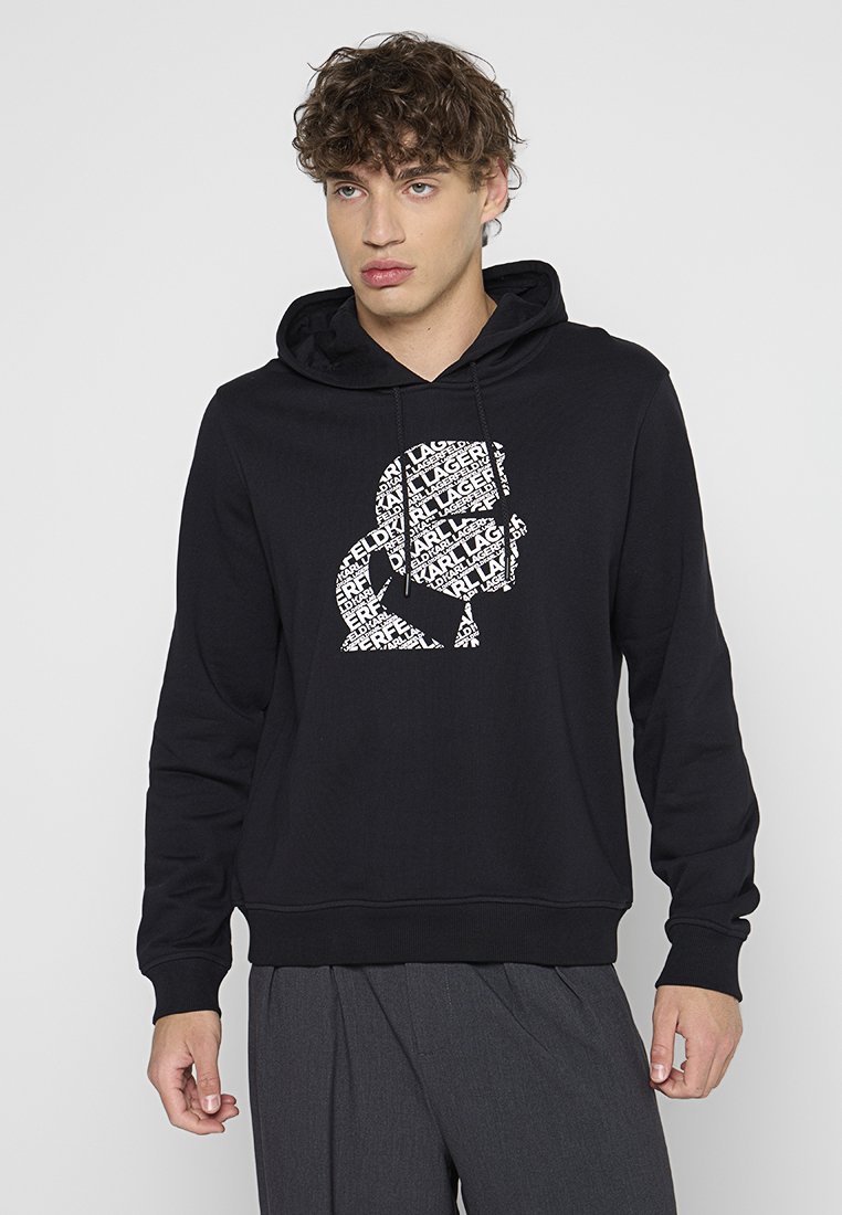 Hoodie noir en coton, avec un design graphique blanc représentant un visage constitué de texte répété. Comprend une capuche avec cordon de serrage et un ourlet côtelé.