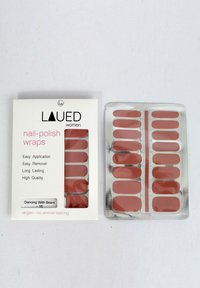 Nagellackfolien in einem sanften Rosaton. Die Verpackung enthält ein Plastikblatt mit mehreren ovalen Folien und eine Kartonbox mit der Aufschrift "Tanzen mit Bären."