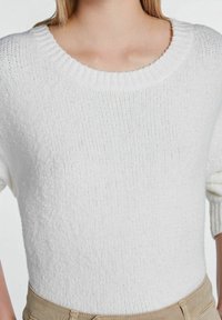 Suéter blanco de punto con cuello redondo, que presenta una tela texturizada y mangas cortas ligeramente abullonadas.