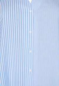 Camicia a strisce azzurre e bianche con bottoni sul davanti, caratterizzata da una texture liscia e linee verticali uniformi.