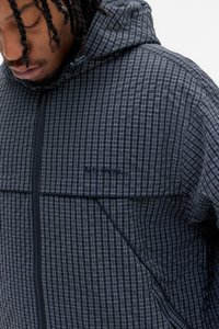 Casaco preto com capuz e padrão de grelha, apresentando fecho de zíper, tecido texturizado e um logo sutil no peito.