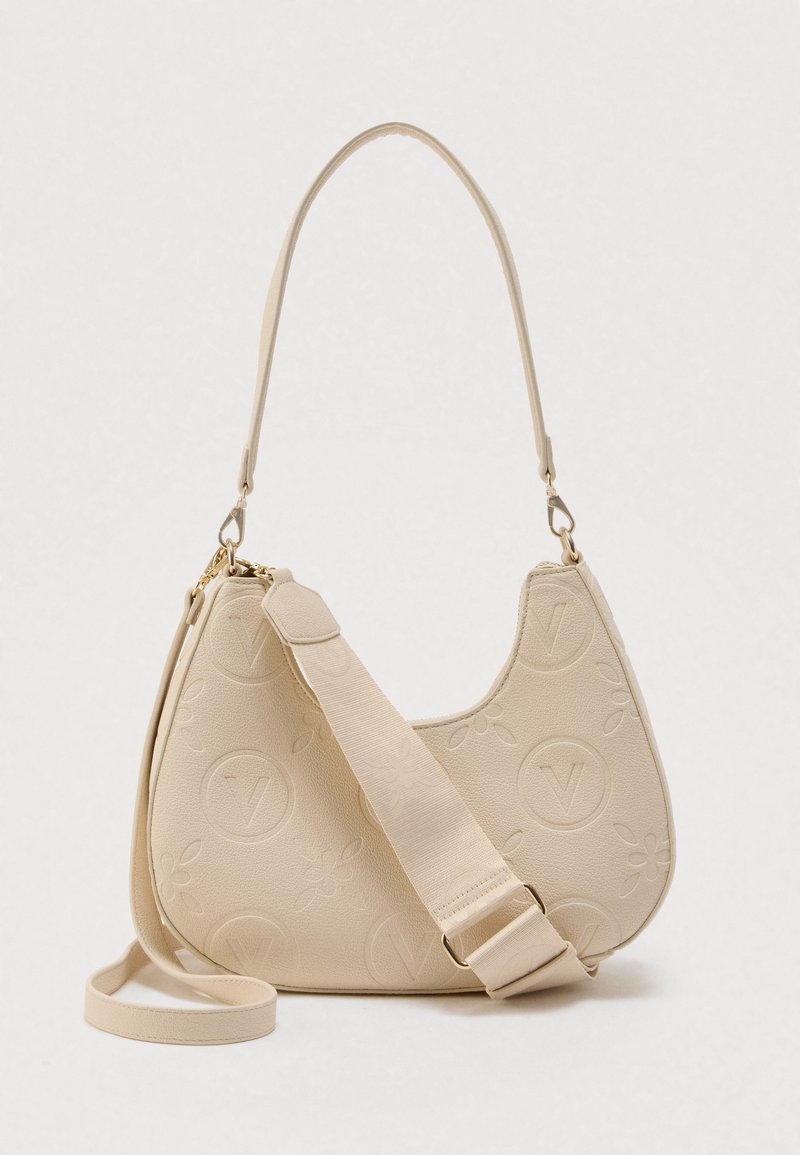 Bež torbica v obliki polmesečja z reliefnimi cvetličnimi in krožnimi logotipi, ki ima dva snemljiva traka, enega tanka in enega širokega z nastavljivo zaponko.
