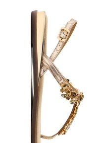 Sandal beige con suola piatta, dotata di una fibbia dorata, cinturini trasparenti e un accento decorativo di cristalli nella zona delle dita.